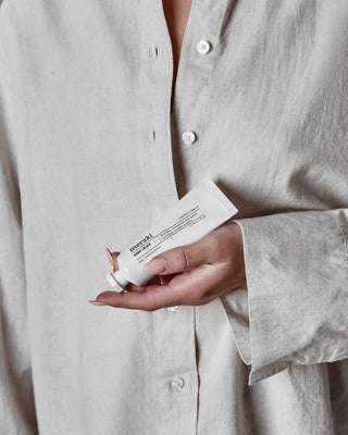 Persoon doseert crème uit een witte tube Meraki Hand Cream Northern Dawn in de hand