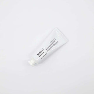 Witte tube Meraki Hand Cream Northern Dawn schuin liggend op een witte achtergrond