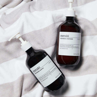 Meraki Moisturising Conditioner en shampoo in pompflacons op gestreepte stof