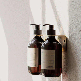 Meraki Northern Dawn shampoo en bodywash in pompflacons aan een gouden wandhouder