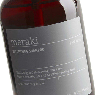 Close-up van het voorste etiket op de flacon Meraki volumising shampoo