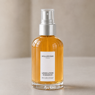 Detailbeeld van Millefiori Milano Home Spray 100 ml Legni e Fiori dArancio met amberkleurig glas, etiket en zilveren verstuiver onder transparante dop.
