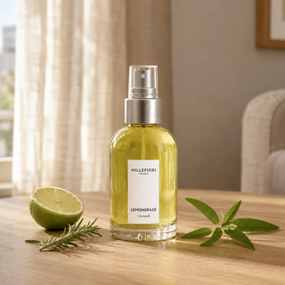 Millefiori Milano Home Spray 100 ml Lemon Grass op een houten tafeltje met limoen, rozemarijn en verbena.
