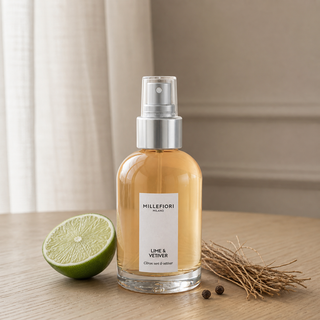 Millefiori Milano Home Spray 100 ml Lime & Vetiver op een eiken tafeltje met limoen, vetiverwortels en peperkorrels.