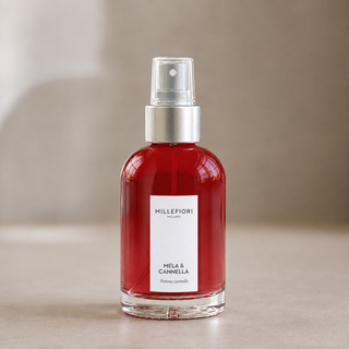 Millefiori Milano Home Spray 100 ml Mela & Cannella van dichtbij met rood glas, wit etiket en zilveren verstuiver onder een transparante dop.