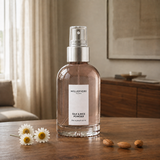 Millefiori Silk & Rice Powder roomspray op een houten console met kamille en amandelen.