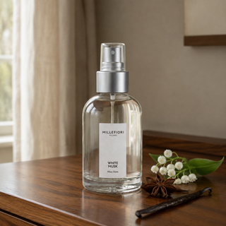 Millefiori White Musk roomspray op een houten console met lelietje-van-dalen, steranijs en vanille.