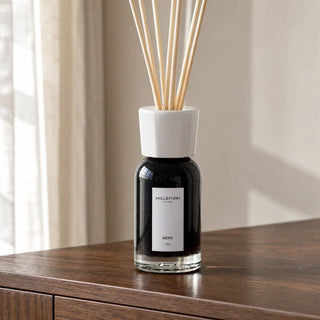 Detail van Millefiori Milano Reed Diffuser 100 ml Nero met witte kraag, etiket en raamreflecties in het donkere glas.