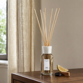 Millefiori Ambra Minerale geurstokjes op een houten console met citrus, tonkabonen en cederhout.