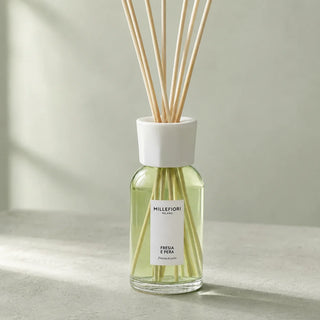 Detail van de glazen flacon, witte kraag en naturel geurstokjes van Millefiori Milano Reed Diffuser 250 ml Fresia e Pera.