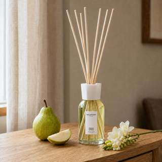 Millefiori Milano Reed Diffuser 250 ml Fresia e Pera op een houten console met peer en freesia in zacht raamlicht.