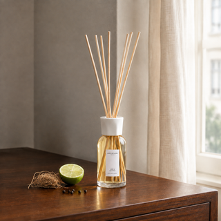 Millefiori Lime & Vetiver geurstokjes op een houten console met limoen, vetiver en peper.