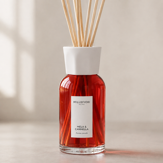 Detail van Millefiori Milano Reed Diffuser 250 ml Mela & Cannella met rood glas, een wit etiket en een witte gefacetteerde kraag.