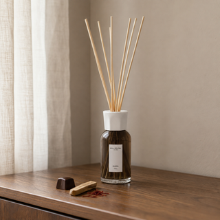 Millefiori Milano Reed Diffuser 250 ml Ombra op een houten console met chocoladepraline, sandelhout en saffraan in zacht raamlicht.