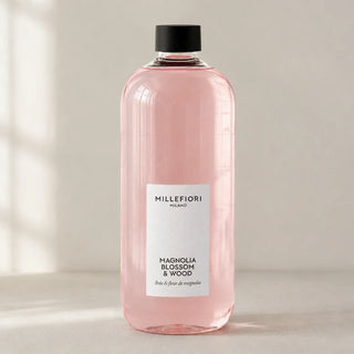 Detail van Milano Refill 500 ml Magnolia Blossom & Wood van Millefiori met zwarte schroefdop, laag wit etiket en navulfles in zacht raamlicht.