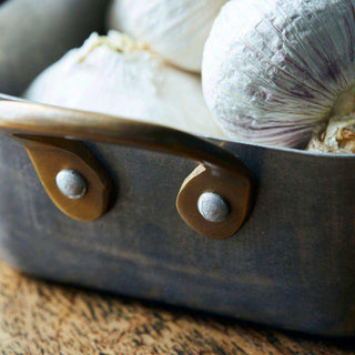 Close-up van mini braadschaal met knoflookbollen en geklonken zijgrepen