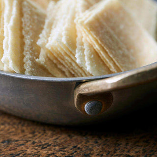 Detail van een mini pan met geribbelde chips en een goudkleurige handgreep