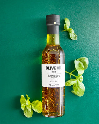 Olijfolie met basilicum 250ml van Nicolas Vahe, gepresenteerd in een culinaire keuken- of tafelsetting