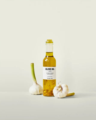 Olijfolie met knoflook 250ml van Nicolas Vahe, gepresenteerd in een culinaire keuken- of tafelsetting