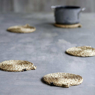 Ronde gevlochten rieten onderzetters op grijze tafel, natuurlijk en stoer design voor keuken of eetkamer