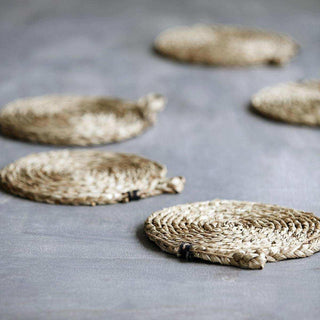 Ronde gevlochten placemats van natuurlijk materiaal op grijze ondergrond