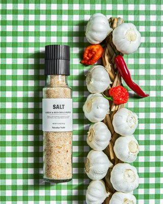 Zoutmolen met knoflook en rode chilipeper naast knoflookbollen en rode pepers